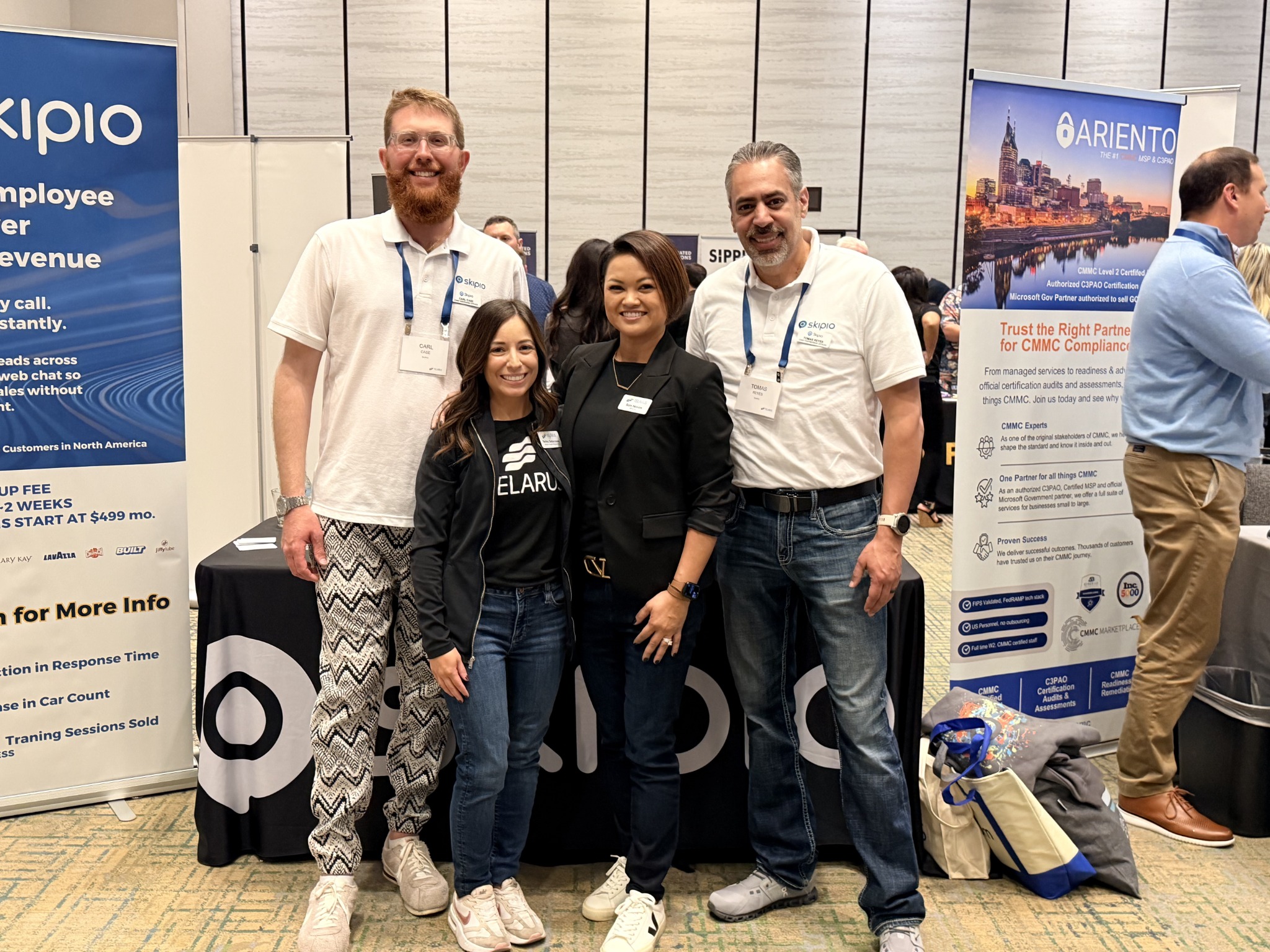 Tomas and a group at an exhibition booth with Skipio branding